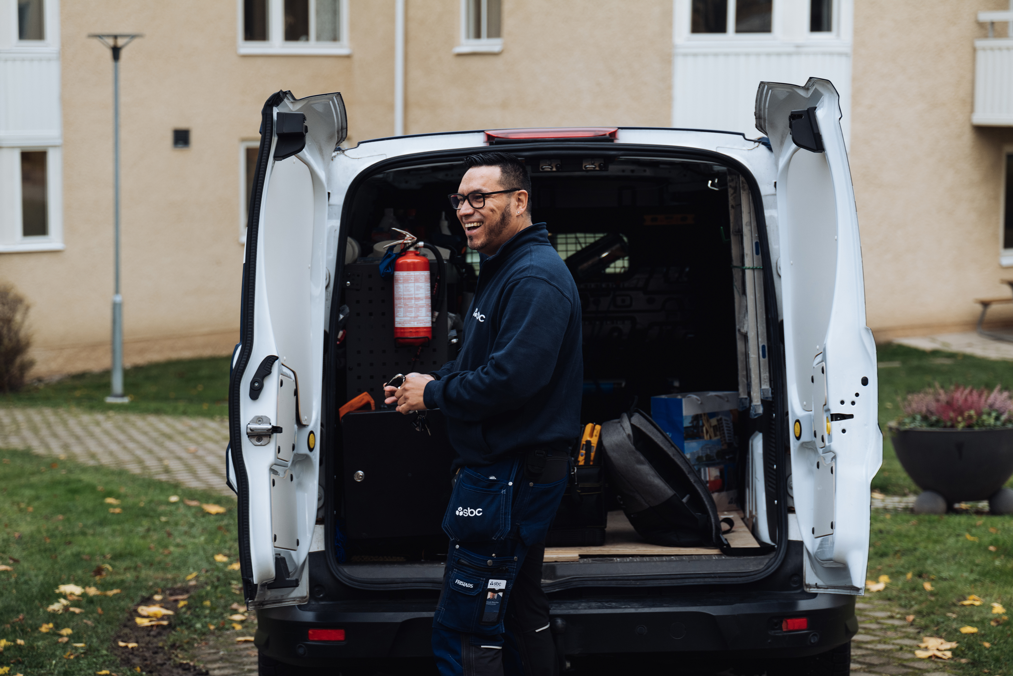 Skrattande fastighetsskötare hämtar verktyg i arbetsbilen