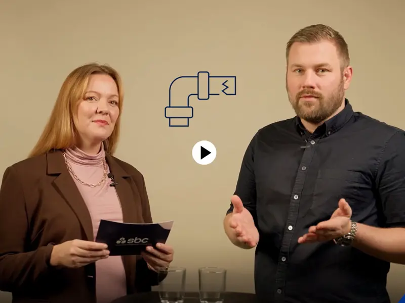 En man och en kvinna står i en studio och samtalar om vad man ska tänka på inför ett stambyte i en brf.