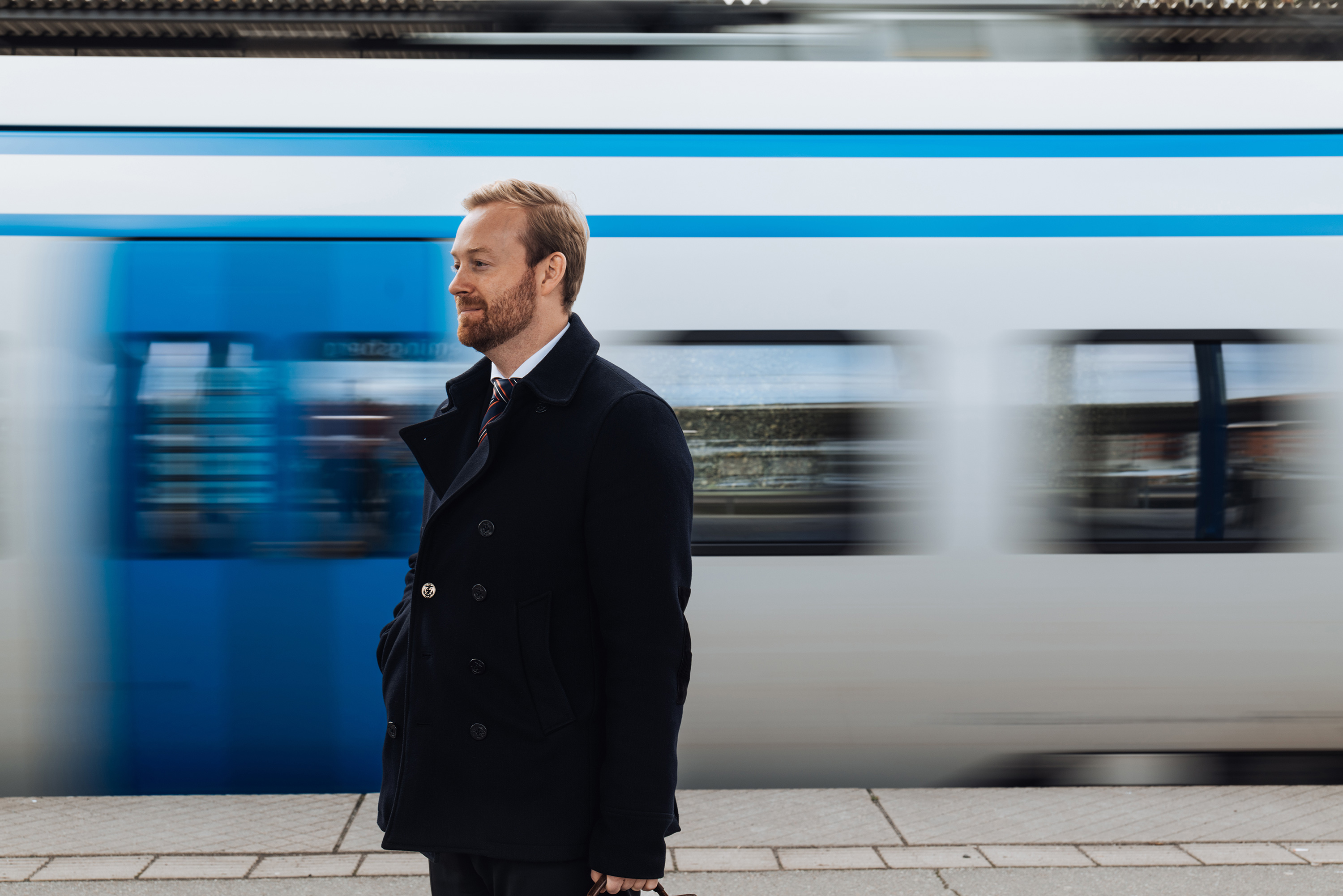Jurist står på perrong när ett pendeltåg åker förbi