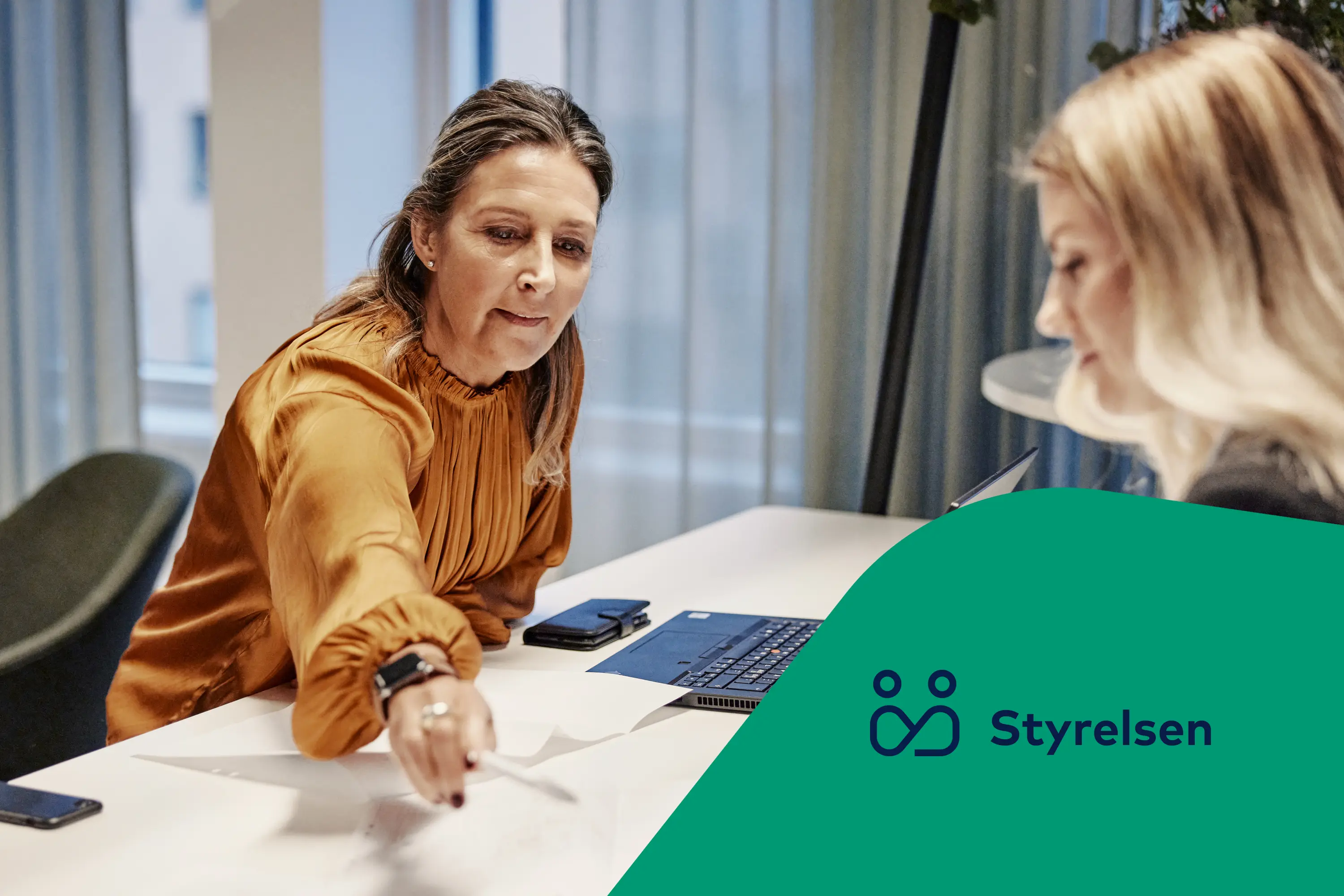 Två kvinnor arbetar vid ett bord med papper och laptop. Ikon för Styrelsen.
