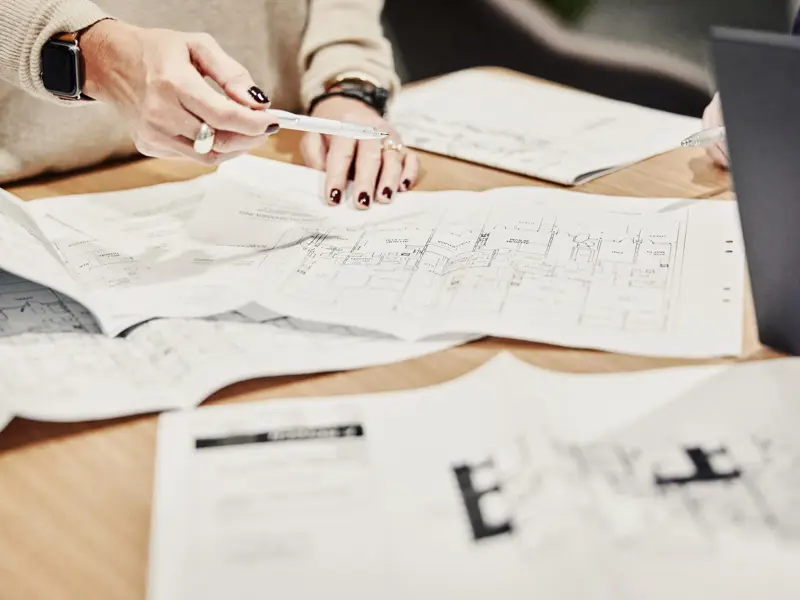 Kvinnliga händer pekar på byggnadsritningar