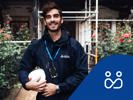 SBCs byggprojektledare Patrik står framför en fastighet med byggnadsställning och rosenrabatt. Projektledningsikon.