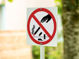 Skylt med ett rött streck över en hand som kastar cigarettfimpar.