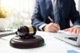 Jurist sitter vid skrivbord med dator och domstolsklubba på