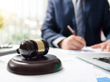 Jurist sitter vid skrivbord med dator och domstolsklubba på