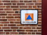 Skylt som informerar om att skyddsrum finns i byggnanden
