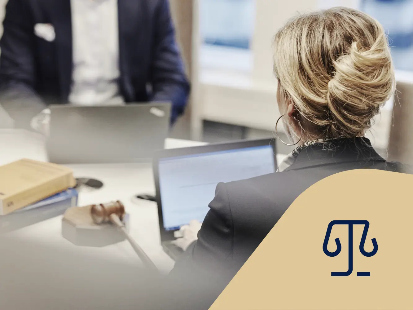 Kvinnlig jurist sitter vid en laptop med en ordförandeklubba bredvid sig. Juridikikon.