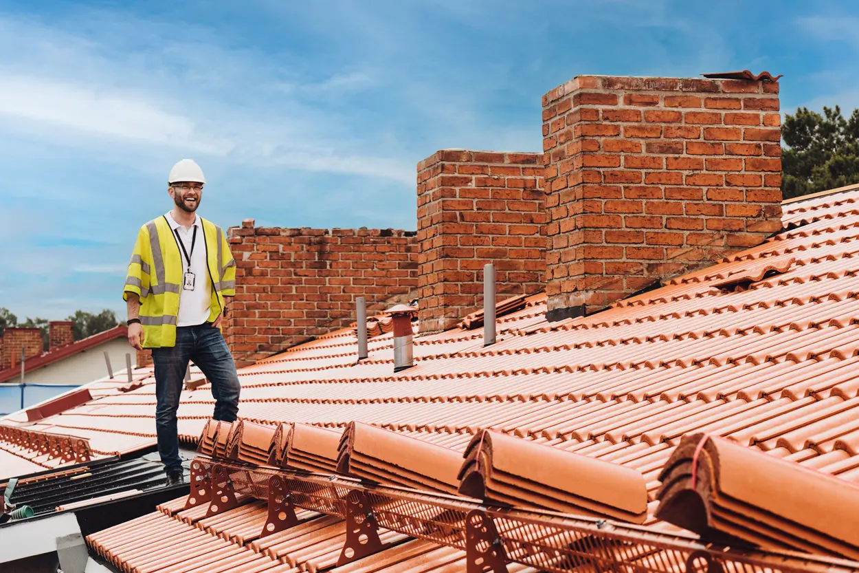 Manlig projektledare iklädd bygghjälm står på taket i en bostadsrättsförening