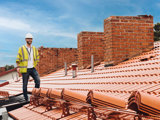 Manlig projektledare iklädd bygghjälm står på taket i en bostadsrättsförening 