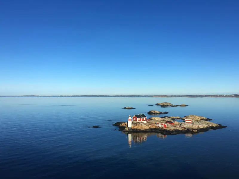 Liten skärgårdsö bebyggd med små röda trähus med vita knutar samt en fyr