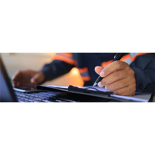 Person skriver trygghetscertifikat på papper med en dator framför sig