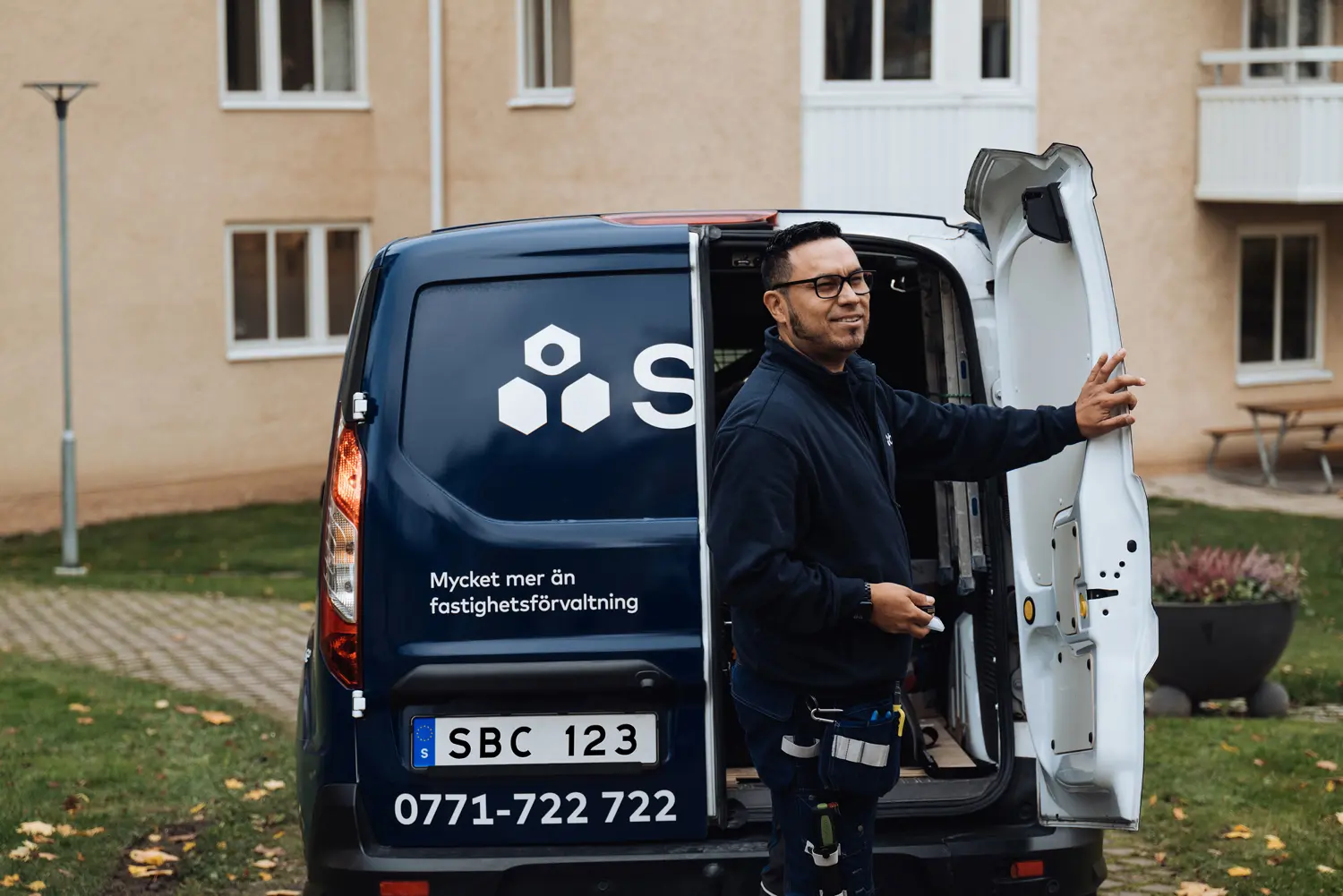 Fastighetsskötare från SBC stänger baklucka till bil