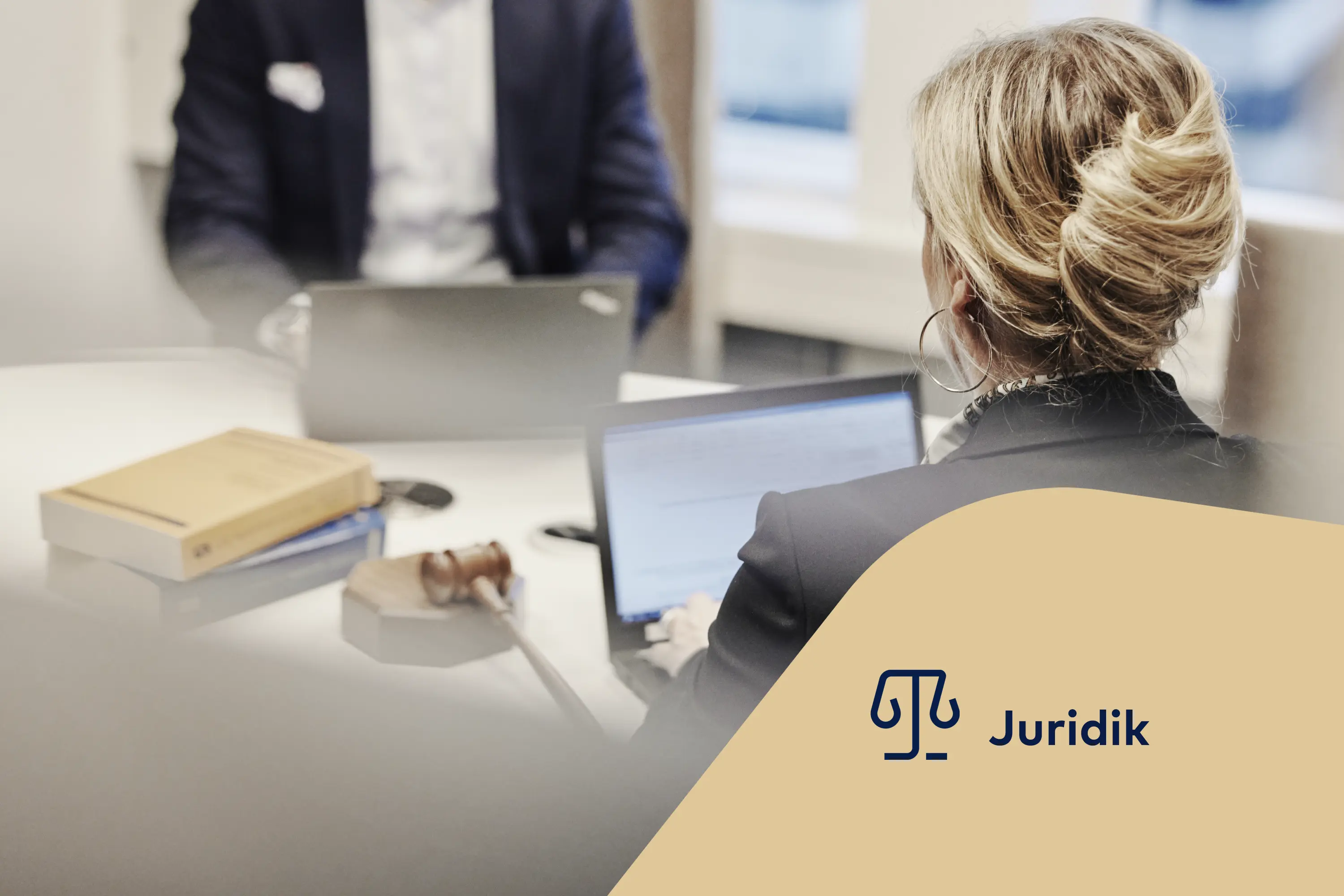 Kvinnlig jurist sitter vid en laptop med en ordförandeklubba bredvid sig. Juridikikon.