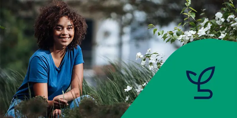 Kvinna sitter på huk i gräset med en fastighet i bakgrunden. Ikon för energi och miljö.