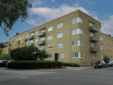 Flerbostadshus i tre våningar med gul tegelfasad. Tillhör BRF Åsbo.