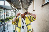 Manlig projektledare går i byggnadsställning och rättar till sin bygghjälm