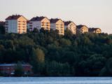 Höghus med bostadsrätter på en grön kulle vid vattnet.