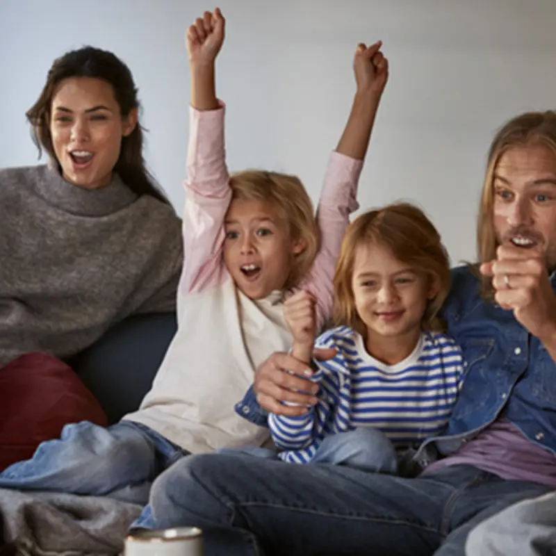 Glad barnfamilj har fredagsmys framför tvn