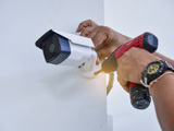Borrmaskin används för att sätta upp övervakningskamera på vägg