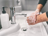 Händer som tvättas med tvål i handfat