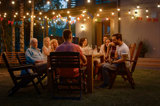en grupp personer samlade vid ett bord på en uteplats en sommarkväll